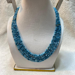Blue beaded necklace on a white mannequin bust against a light background