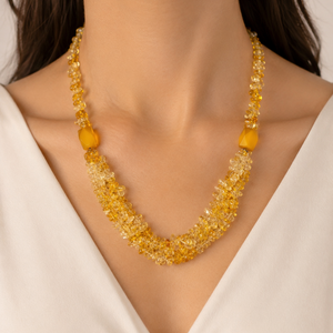 Necklace with yellow beads worn by a person against a neutral background