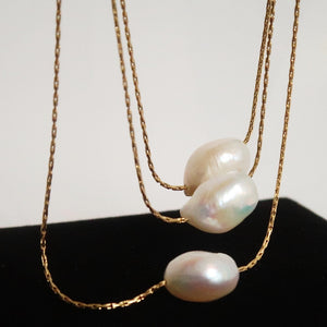 Close-up of dainty freshwater pearl pendant necklace on gold chain