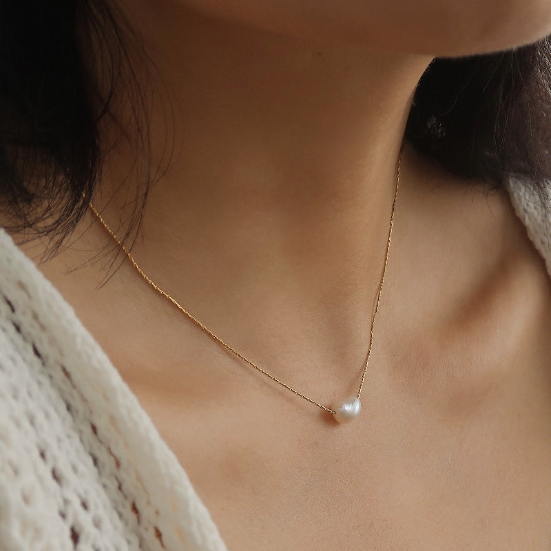 Close-up of dainty freshwater pearl pendant necklace on gold chain