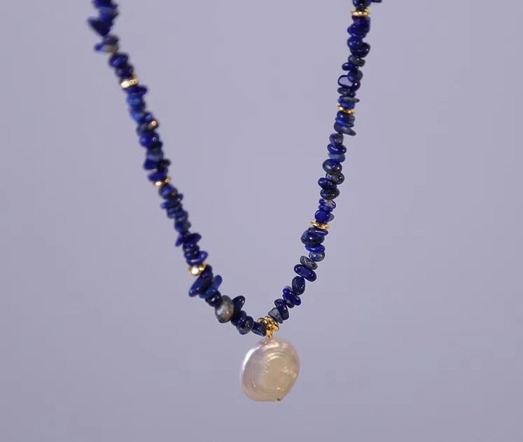 Woman wearing elegant baroque freshwater pearl pendant necklace with blue lapis lazuli chip beads