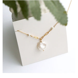 Dainty gold chain necklace with freshwater pearl pendant, worn on a woman's neck, showcasing elegance and minimalist style.