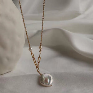 Dainty gold chain necklace with freshwater pearl pendant, worn on a woman's neck, showcasing elegance and minimalist style.