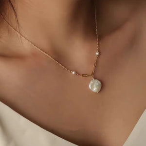 Dainty gold chain necklace with freshwater pearl pendant, worn on a woman's neck, showcasing elegance and minimalist style.