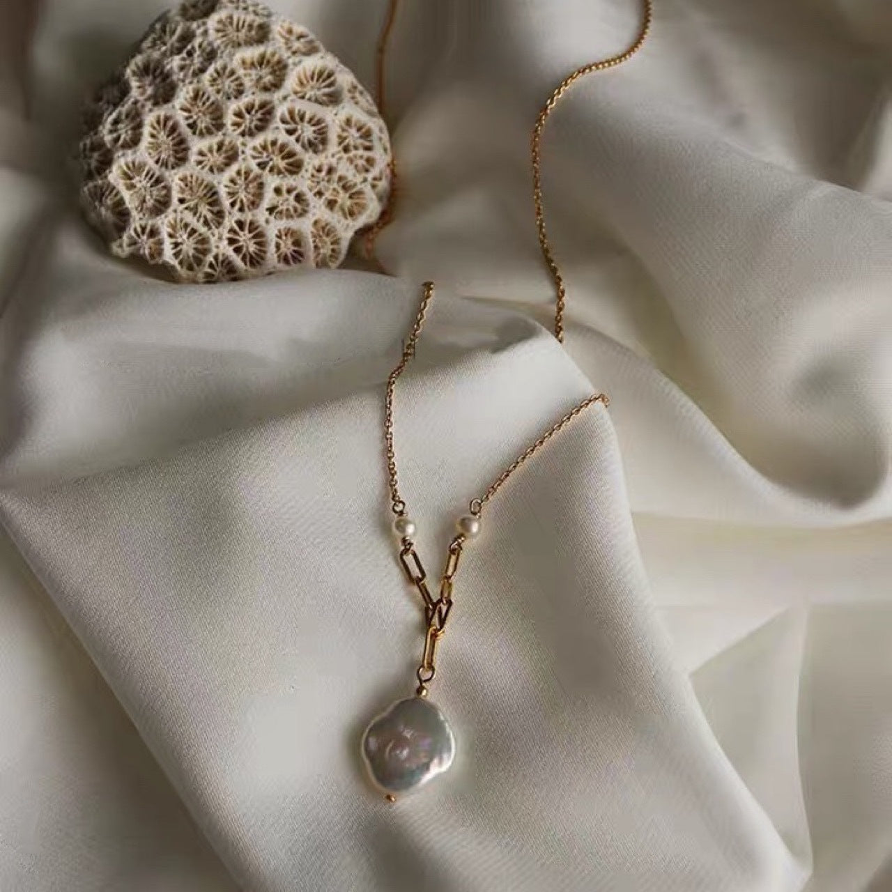 Dainty gold chain necklace with freshwater pearl pendant, worn on a woman's neck, showcasing elegance and minimalist style.