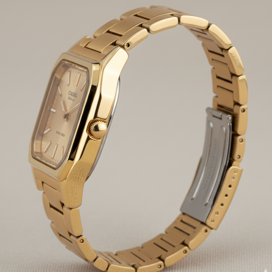 Gold watch with a metallic band on a beige background