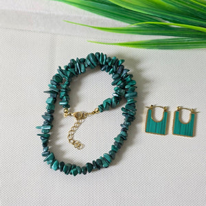 Teal beaded bracelet and earrings on a light gray surface with green leaves.
