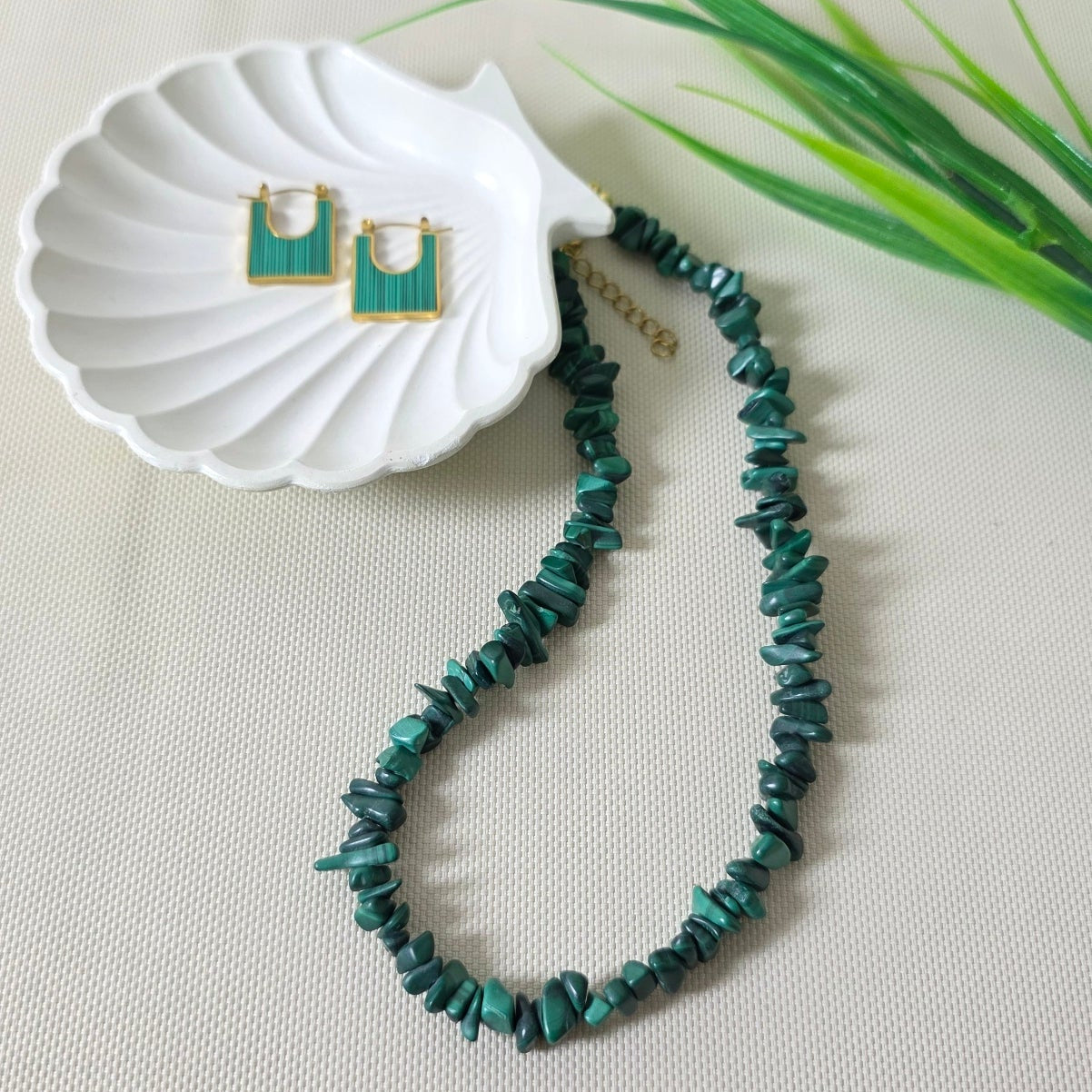 Bracelet with green beads on a white shell against a light background