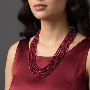 Woman wearing a deep red beaded necklace against a neutral background