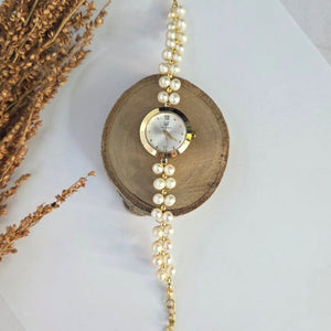 Gold bracelet with a central crystal on a wooden block, surrounded by dried lavender on a light background