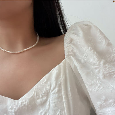 Close-up of a freshwater pearl necklace with gold toggle clasp on a soft background.