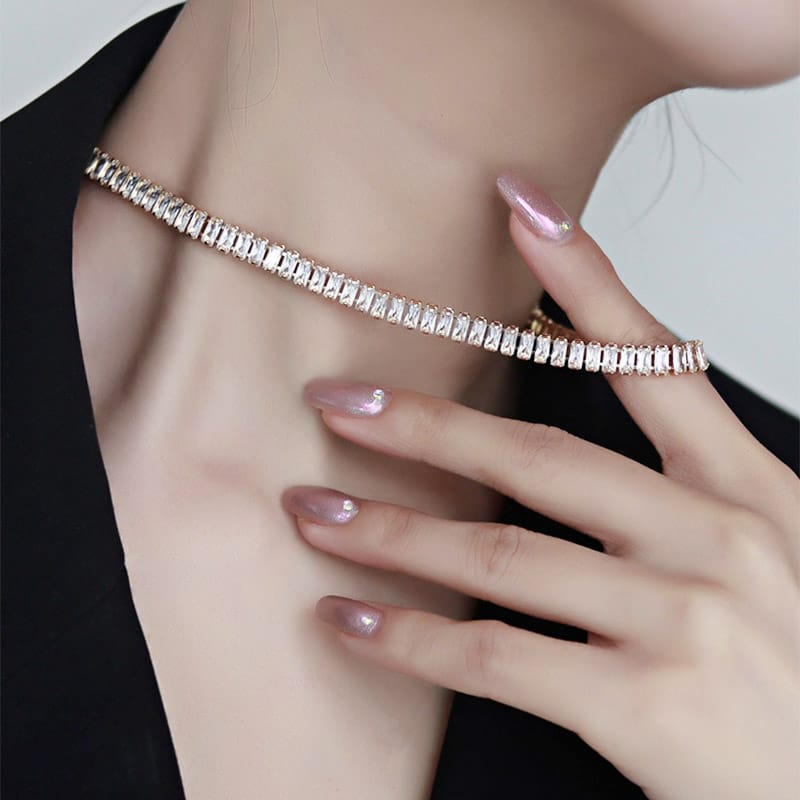 Close-up of a person wearing a sparkling gold bracelet on a plain background