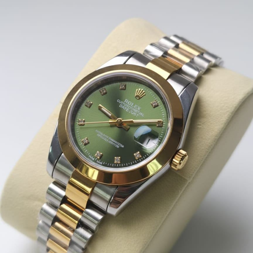 Two-tone gold and silver watch with a green face on a beige cushion.