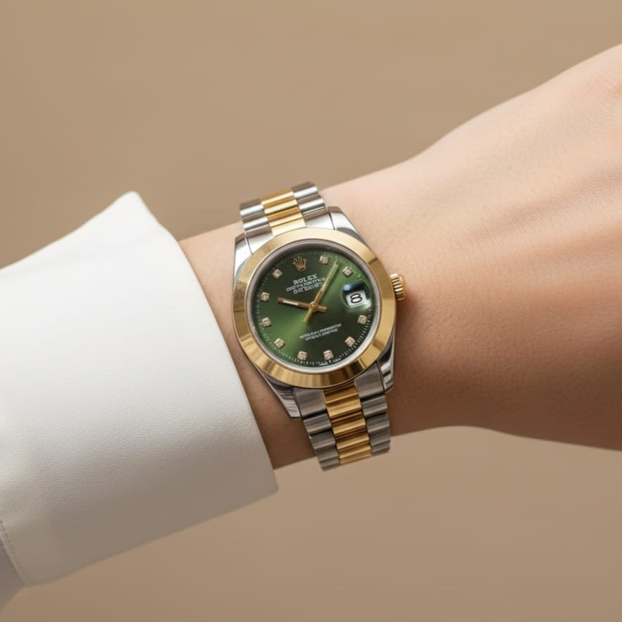 Two-tone watch with a green face on a wrist against a beige background