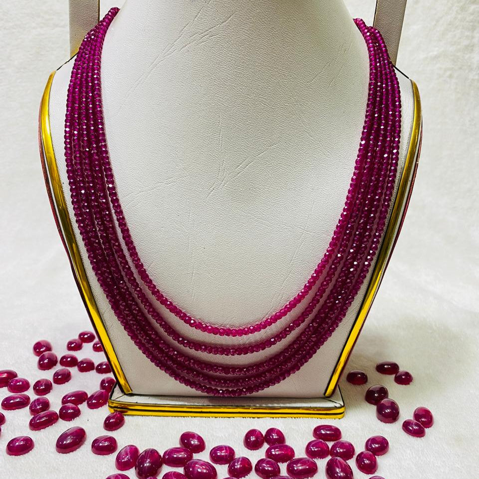 Multi-strand ruby beads necklace with faceted shine displayed on jewelry stand