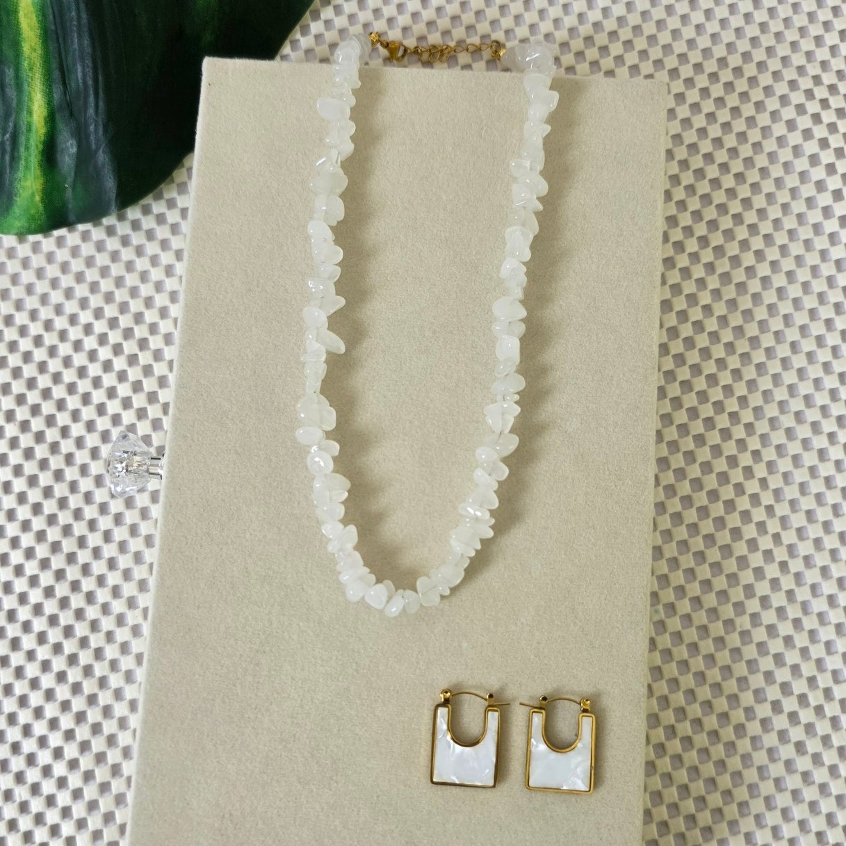 Necklace and earrings set on a beige card with a textured background