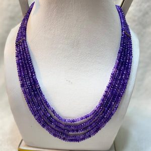 Purple beaded necklace on a white mannequin bust