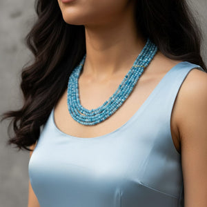 Model wearing a multi-layer blue jade mala necklace with elegant light blue outfit.
