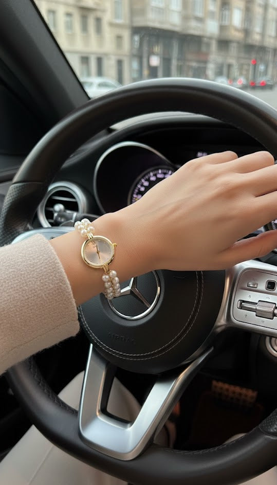 Hand with a gold watch on a car steering wheel in an urban setting