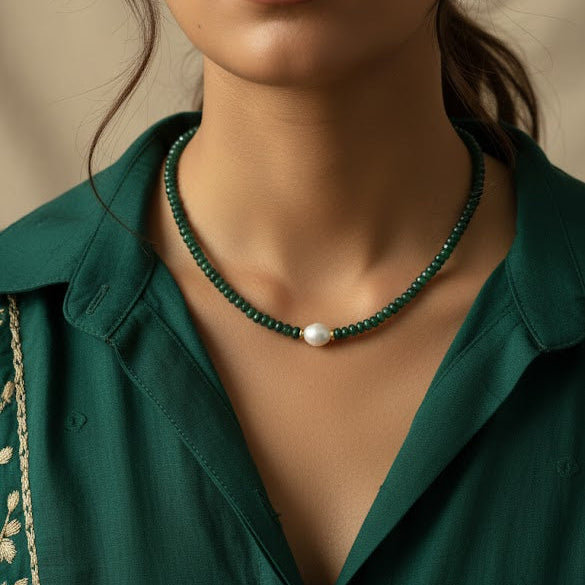 Woman wearing a green shirt and necklace with a neutral background