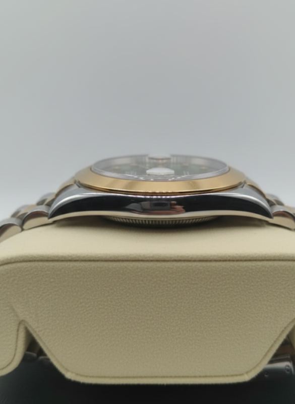 Close-up of a watch with a gold and silver design on a beige cushion.