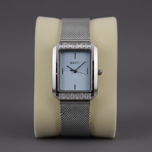 Silver watch with a rectangular face on a beige cushion against a dark background