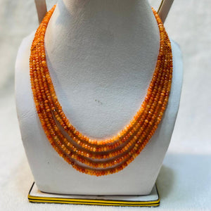Orange beaded necklace on a mannequin bust against a white background
