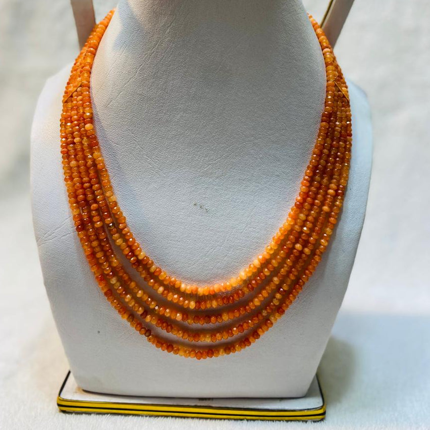 Orange beaded necklace on a mannequin bust against a white background